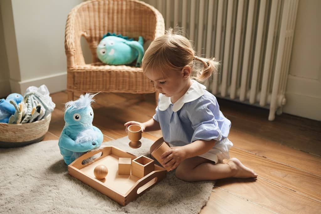 Petite fille jouant tranquillement dans sa chambre avec des jeux en bois naturel